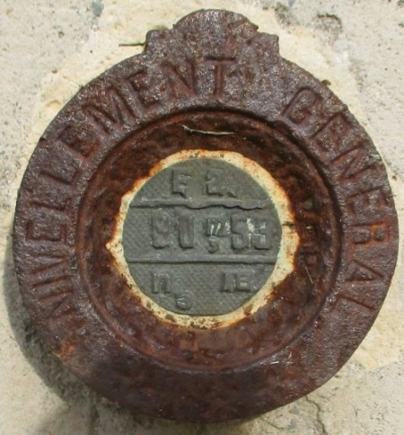 Balise du nivellement général. Un rond en fonte plaqué contre le mur ouest de la chapelle, comportant l'inscription 80m53